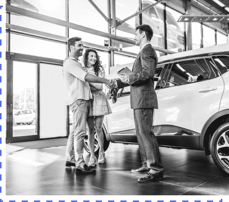 Dealer and customers closing a deal in a car dealership by shaking hands
